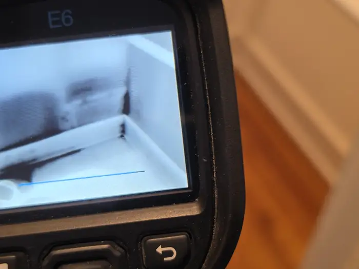 Thermal imaging camera displaying the wall and floor near a baseboard